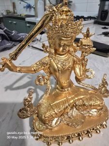 Golden deity statue with ornate details, holding sword and flame object, in kitchen setting.