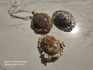 Three vintage brooches with metal frames, ceramic centers, and a $14 price tag attached.