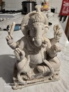 Ganesha Statue on Marble Countertop in Kitchen Setting White Ganesha statue with four arms on marble countertop, kitchen background.