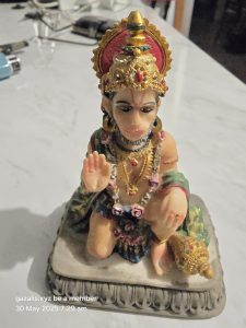 Ornate Seated Figure Statue with Headdress Detailed statue of a seated figure with a red and gold headdress, jewelry, and a small mace.