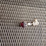 Trio Gemstone on Metallic Weave Three-stone jewelry piece on woven metallic surface, featuring dark red and clear gemstones.