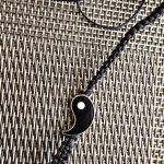 Yin-Yang Braided Bracelet Black braided bracelet with yin-yang symbol on woven surface.