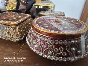 Ornate Gemstone-Embellished Boxes Two ornate boxes with gemstones on a wooden surface with visible inscription and debris.
