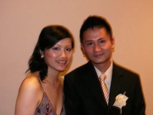 Elegant Couple Smiling Indoors Man in suit and woman in dress posing indoors, both smiling at camera.