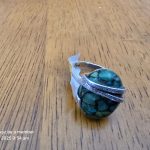 Turquoise Silver Ring Close-Up Turquoise and silver ring on wooden surface, close-up of stone texture and metal pattern.