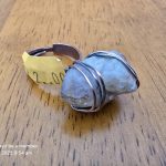 Wire-Wrapped Stone Ring with Price Tag Ring on wood surface with stone wrapped in metal, $2.00 price tag, timestamp visible.